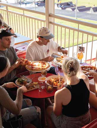 Friends sharing pizza at a table on the Seamore's balcony overlooking Henley Square